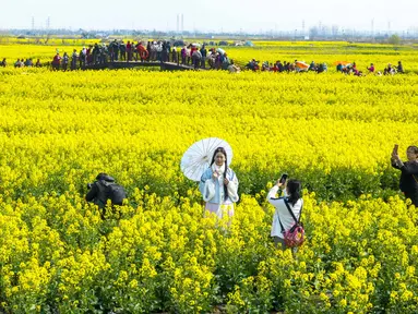 Foto yang diambil pada 19 Maret 2023 ini menunjukkan orang-orang mengambil foto di antara Bunga canola atau dikenal juga dengan nama rapeseed yang bermekaran di area pemandangan Xinghua Qianduo di Taizhou, di provinsi Jiangsu timur China. (Photo by STR / AFP)