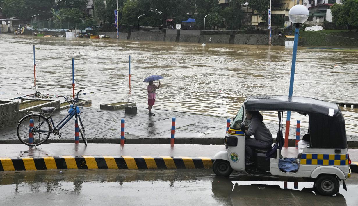 Seorang pria memotret sungai yang meluap akibat curah hujan yang meningkat akibat Topan Doksuri di kota Marikina, Filipina pada Kamis, 27 Juli 2023. (AP Photo/Aaron Favila)