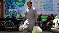 Seorang pria seusai membeli stok makanan di supermarket yang dikelola pemerintah Pakistan di Islamabad, Rabu (16/5). Warga berbelanja untuk memenuhi kebutuhan menyambut Puasa Ramadan yang dimulai pada Kamis (17/5). (AP/Anjum Naveed)