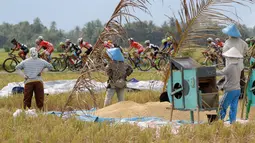 Petani berhenti menjemur gabah untuk menonton balapan Tour de Singkarak 2016 pada Etape 6 dari Padang Pariaman menuju Sawahlunto, Sumatera Barat, Kamis (11/8/2016). (Bola.com/Nicklas Hanoatubun)