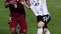 Pemain Argentina Lionel Messi (kanan) dan pemain Venezuela Yangel Herrera berebut bola pada pertandingan sepak bola kualifikasi Piala Dunia 2022 di Stadion La Bombonera, Buenos Aires, Argentina, 25 Maret 2022. Argentina menang 3-0. (ALEJANDRO PAGNI/AFP)