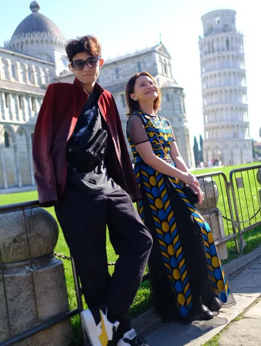 Gaya keren Rossa dan Rizky ketika liburan keluar negeri. Rissa tampil cantik dengan sebuah dress panjang yang semarak berwarna biru-kuning, sedangkan Rizky tampil serba hitam dengan jaket bernuansa gradasi hitam-merahnya. [Foto: Instagram/itsrossa910]