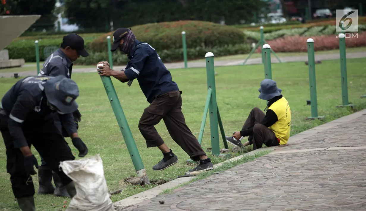 Petugas Unit Pengelola Kawasan (UPK) Monas mencopot pagar pembatas antara jalan dengan taman di kawasan Monas, Jakarta, Jumat (11/1). Pencabutan pagar itu merupakan arahan langsung dari Wakil Gubernur DKI Sandiaga Uno. (Liputan6.com/Arya Manggala)
