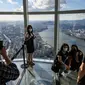 Pengunjung berpose untuk foto di bagian lantai kaca gedung pencakar langit Lotte World Tower 123 lantai di Seoul pada 22 September 2021. Bangunan tertinggi di Korea Selatan tersebut berlokasi di pinggiran Sungai Han, ibu kota Seoul. (Anthony WALLACE / AFP)