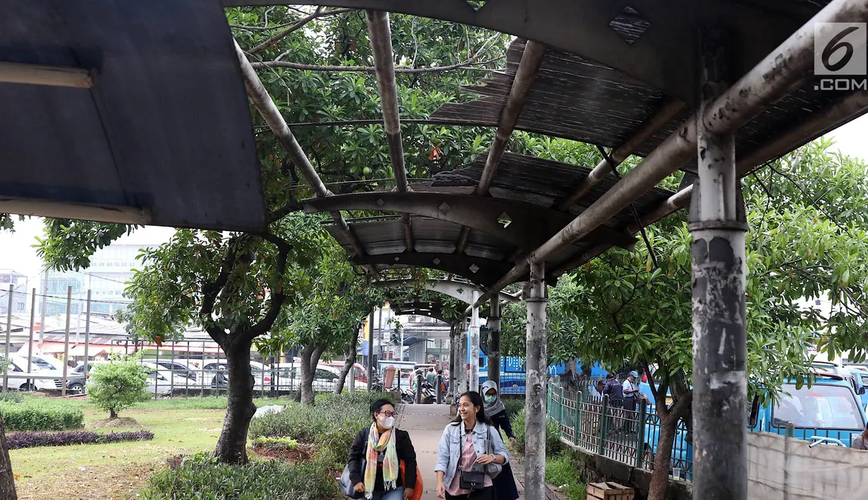 Warga melintasi jalur khusus pejalan kaki di kawasan Kampung Rambutan, Jakarta, Selasa (19/2). Atap rusak yang juga tidak dilengkapi dengan lampu penerangan mengganggu kenyamanan pejalan kaki. (Liputan6.com/Immanuel Antonius)