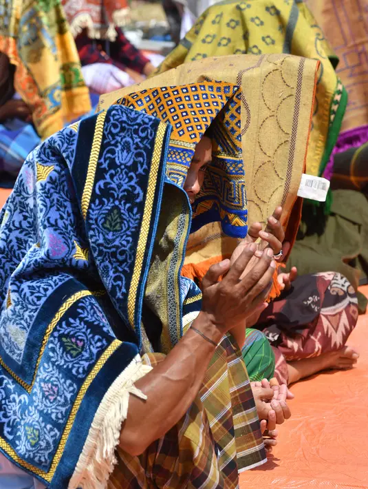 Umat Muslim berdoa saat salat Jumat di sebuah ladang di dekat tempat penampungan sementara setelah gempa di Pemenang, Lombok (10/8). Korban tewas akibat gempa dahsyat 6,9 SR di pulau Lombok melonjak di atas 300 orang. (AFP Photo/Adek Berry)