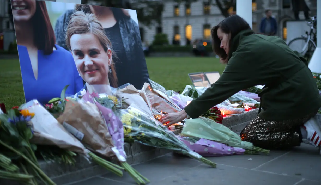 Seorang wanita meletakkan bunga di dekat foto anggota parlemen Inggris, Jo Cox di alun-alun Parlemen, London, Kamis (16/6). Meski sudah dilarikan ke rumah sakit, nyawa Jo Cox tak tertolong dan dinyatakan tewas sejam kemudian. (Daniel Leal-Olivas/AFP)