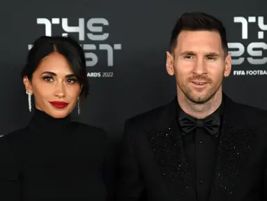 Pemain Paris Saint-Germain asal Argentina, Lionel Messi (kanan) dan istrinya Antonela Roccuzzo berpose setibanya pada acara The Best FIFA Football Awards 2022 di Paris, Prancis, 27 Februari 2023. Messi dan Antonella mencuri perhatian saat menghadiri The Best FIFA Football Awards 2022. (FRANCK FIFE/AFP)