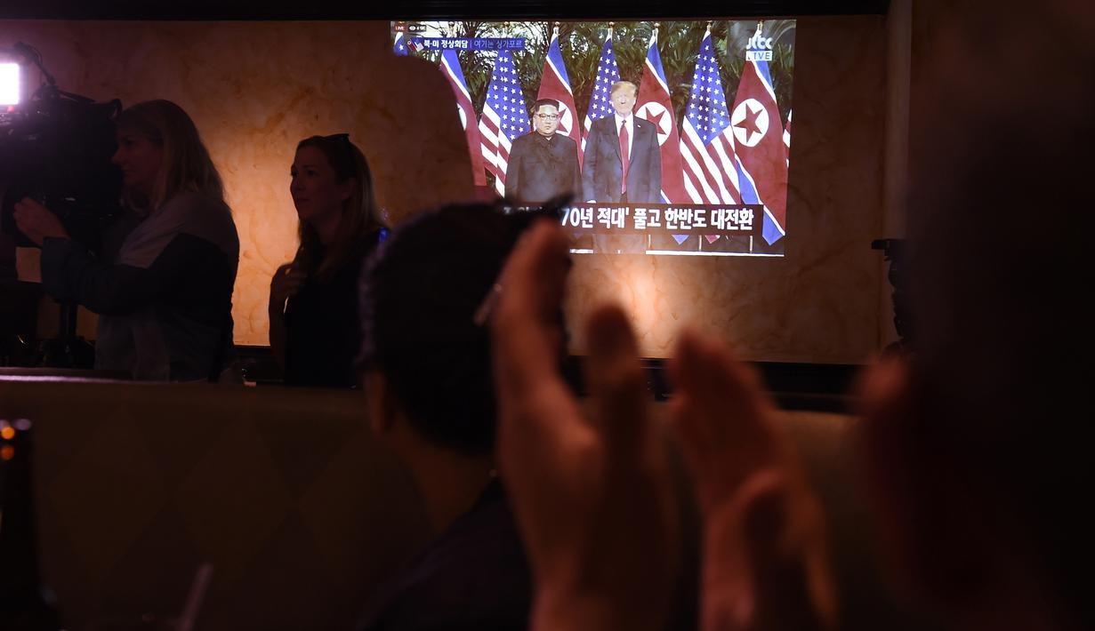 Orang-orang bertepuk tangan menonton pertemuan antara pemimpin Korea Utara Kim Jong-un dan Presiden AS Donald Trump di Koreatown, Los Angeles, Selasa (12/6). Untuk pertama kalinya dalam sejarah, Donald Trump dan Kim Jong-un bertemu. (AFP PHOTO/Robyn Beck)