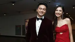 Penampilan pemain film Cinta Laki-Laki Biasa itu makin gagah saat bersanding dengan Mikha Tambayong. Sang kekasih sendiri mengenakan gaun panjang bernuansa merah cerah. (Liputan6.com/IG/@devamahenra).