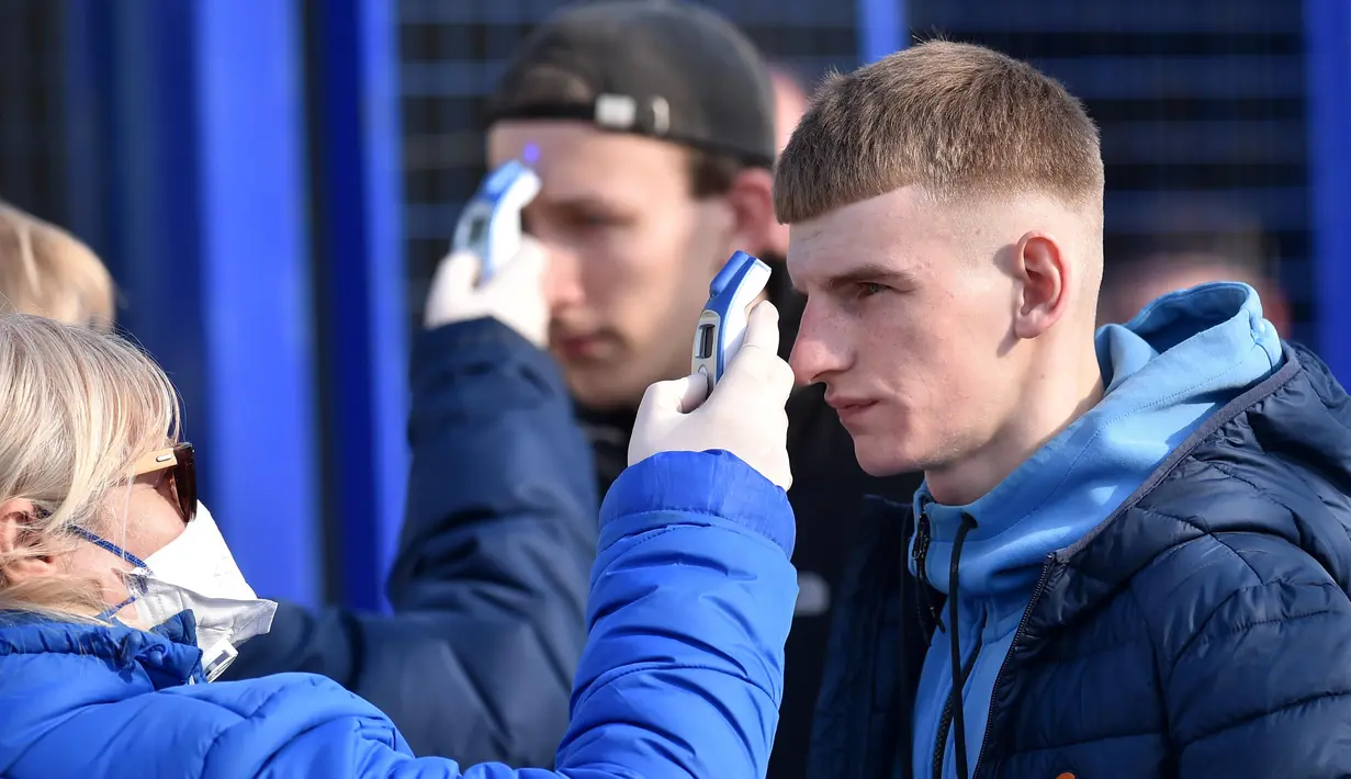 Suporter diperiksa suhu badannya sebelum menyaksikan laga FC Minsk kontra FC Dinamo-Minsk pada laga Liga Belarusia, Sabtu (28/3/2020). Di tengah wabah virus Corona, Liga Belarusia tetap digelar seperti biasa bahkan tetap dipadati suporternya. (AFP/Sergei Gapon)
