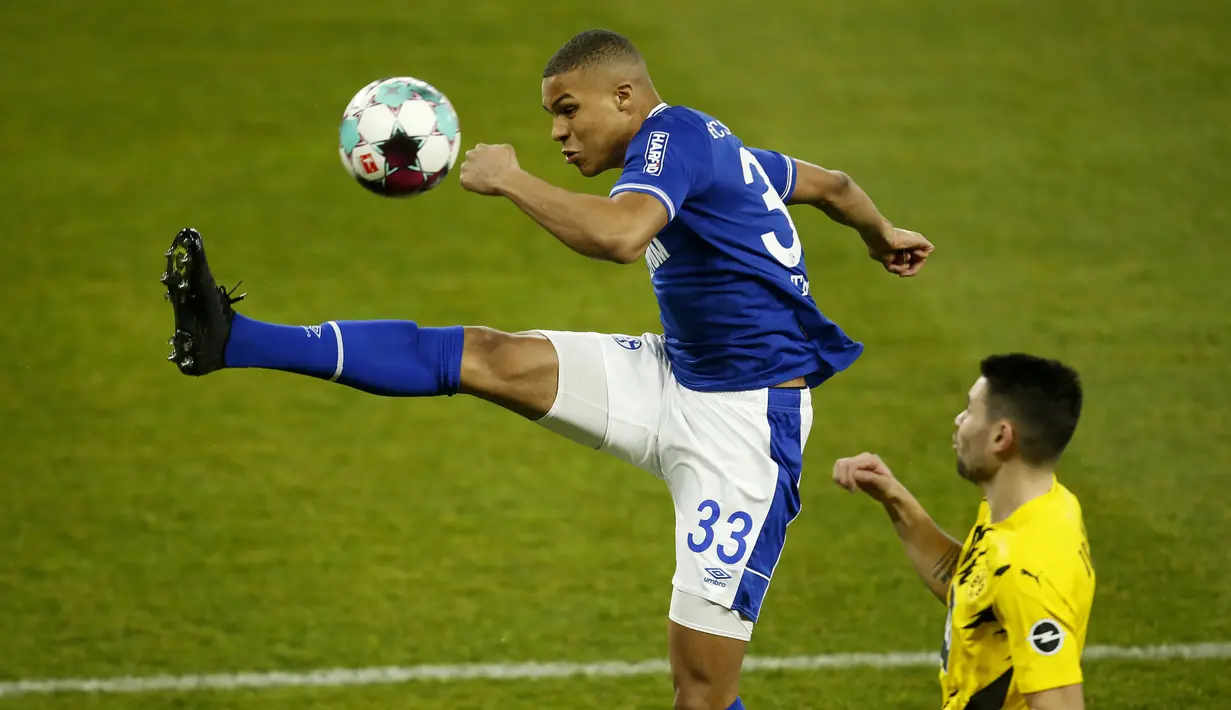 Gelandang Schalke, Malick Thiaw (kiri) membuang bola dari ancaman bek Borussia Dortmund, Raphael Guerreiro dalam laga lanjutan Liga Jerman 2020/21 pekan ke-22 di Veltins Arena, Sabtu (20/2/2021). Schalke kalah 0-4 dari Borussia Dortmund. (AP/Leon Kuegeler/Pool)