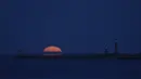 Bulan purnama yang dikenal sebagai Harvest moon terbit di atas pelabuhan Whitby, di Whitby, Inggris, Senin (20/9/2021). Bulan purnama Harvest Moon biasanya terjadi di bulan September, namun kadang juga terlambat hingga ke Oktober. (AP Photo/Alastair Grant)