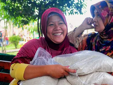 Kegembiraan terpancar usai mendapat beras saat operasi pasar beras oleh BULOG di Lenteng Agung, Jakarta, Senin (2/3/2015). Operasi ini digelar sebagai upaya menurunkan harga beras yang terus naik.(Liputan6.com/Yoppy Renato)