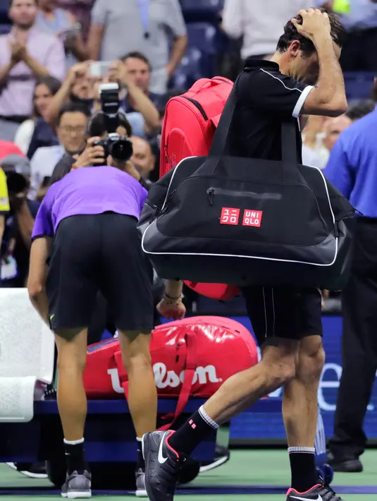Petenis Roger Federer tertunduk saat berjalan keluar lapangan usai kalah dari Grigor Dimitrov pada perempat final turnamen tenis AS Terbuka 2019 di New York, Amerika Serikat, Selasa (3/9/2019). Dimitrov menang 3-6, 6-4, 6-3, 6-4, 6-2. (AP Photo/Charles Krupa)