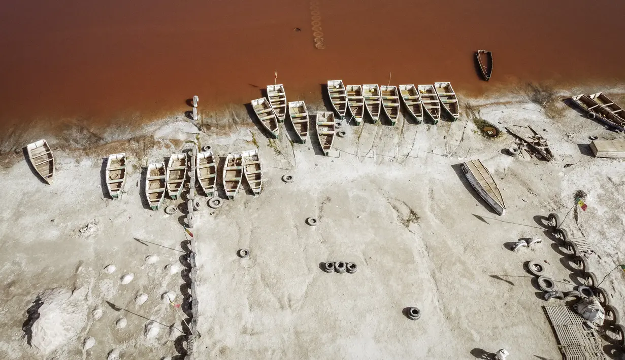 Pemandangan arial ini menunjukkan deretan perahu yang digunakan untuk memanen garam di Danau Retba (Danau Merah Muda) di Senegal pada 16 Maret 2021. Kandungan garam Danau Reba sangat tinggi, yakni 40 persen, bersaing dengan Laut Mati, bahkan bisa melampauinya ketika musim kering. (MARCO LONGARI/AFP)