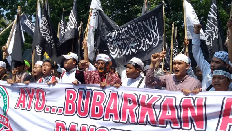 Sejumlah massa membawa bendera dengan tulisan kalimat tauhid di Jalan Medan Merdeka. (Liputan6.com/Ika Defianti)