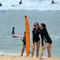 Dua turis wanita berpose saat difoto di pantai Kuta di pulau pariwisata Indonesia di Bali (4/1). Daerah ini merupakan tujuan wisata turis mancanegara dan telah menjadi objek wisata andalan Pulau Bali sejak awal tahun 1970-an. (AFP Photo/Sony Tunbelaka)