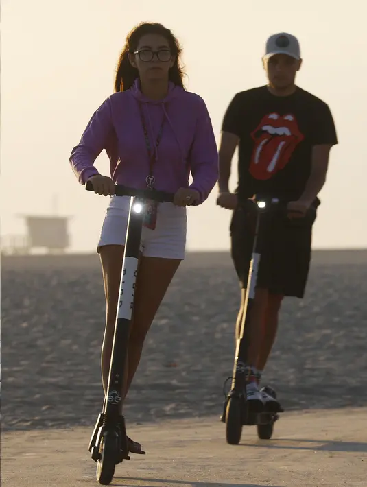 Pengendara menaiki skuter listrik  di sepanjang Venice Beach, Los Angeles, 13 Agustus 2018. Pengendara banyak yang mengabaikan keselamatan seperti tidak mengenakan helm, sebagian juga terjatuh dari skuternya. (Mario Tama/Getty Images/AFP)