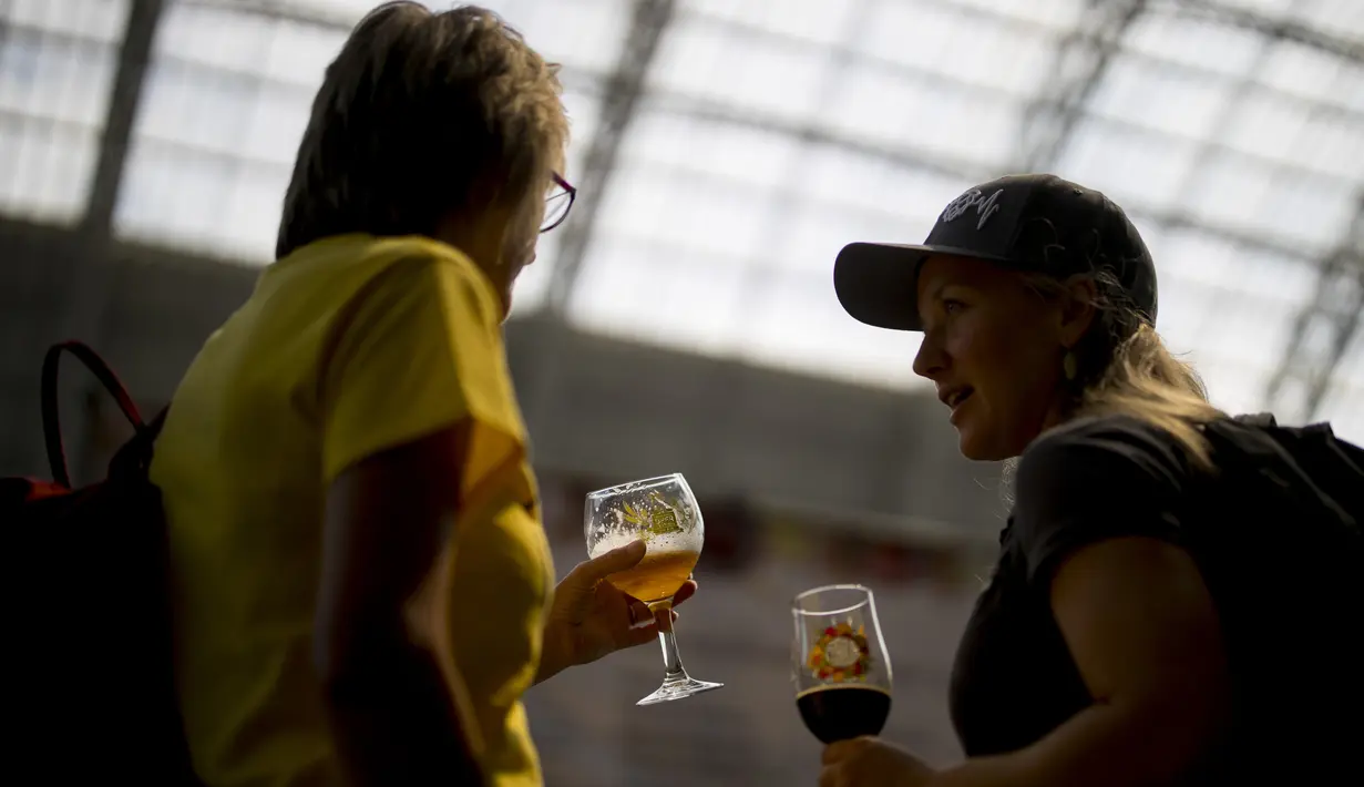 Dua wanita berbincang saat menikmati bir selama The Great British Beer Festival di London (6/8/2019). Great British Beer Festival, yang diselenggarakan CAMRA, menyediakan ratusan bir putih asli, bir internasional dan sari buah asli dan perries. (AFP Photo/Tolga Akmen)