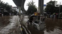 Pedagang mendorong gerobaknya saat melewati banjir di kawasan Tendean Jakarta, Sabtu (20/2/2021). Curah hujan yang tinggi menyebabkan banjir setinggi orang dewasa di kawasan Tendean. (Liputan6.com/Johan Tallo)