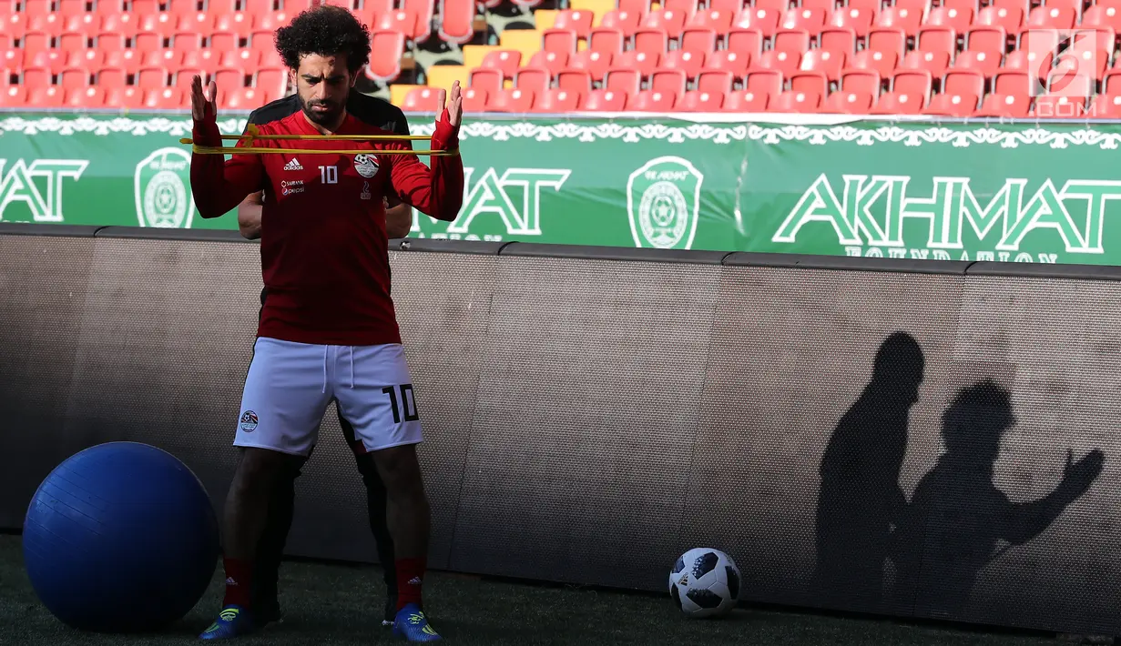 Pemain timnas Mesir Mohamed Salah bersama tim kesehatan melatih bahunya selama sesi pelatihan di stadion Akhmat Arena di Grozny (12/6). Meski masih dibekap cedera bahu, Salah tetap optimis dapat tampil di Piala Dunia 2018 Rusia. (AFP Photo/Karim Jaafar)