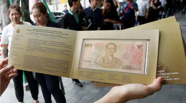 Seorang warga menunjukkan uang kertas 100 baht yang bergambar mendiang raja Thailand Bhumibol Adulyadej di Bangkok, Thailand (18/10). Uang 100 baht edisi ini dibuat untuk memperingati ulang tahun raja ke-84. (Reuters/Edgar Su)