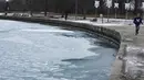 Salju dan es menutupi Danau Michigan saat seorang pria berlari di Pantai Montrose di Chicago (17/1/2022). Badai salju Chicago diperkirakan akan membawa hingga 5 inci di sepanjang Danau Michigan. (AP Photo/Nam Y. Huh)