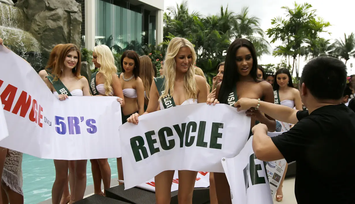 Kontestan Miss Earth 2017, Miss USA Andreia Gibau, dan Miss Belgia Lauralyn Vermeersch memegang slogan saat melakukan persiapan untuk sesi pemotretan dengan bikini di tepi kolam renang hotel di Manila, Filipina, Senin (30/10). (AP/Aaron Favila)