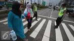 Petugas kepolisian membantu warga menyeberang jalan di Perempatan Cileunyi, Jawa Barat, Jumat (1/7). Mulai banyaknya kendaraan pemudik membuat petugas kepolisian membantu pejalan kaki yang ingin menyeberang. (Liputan6.com/Immanuel Antonius) 