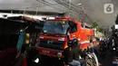 Pengendara melintas saat petugas berusaha memadamkan api  di Gudang JNE Express yang terbakar di Jalan Pekapuran Raya, Depok, pada Senin (12/9/2022). Polisi juga berada di sekitar lokasi untuk mengatur lalu lintas. (Liputan6.com/Herman Zakharia)