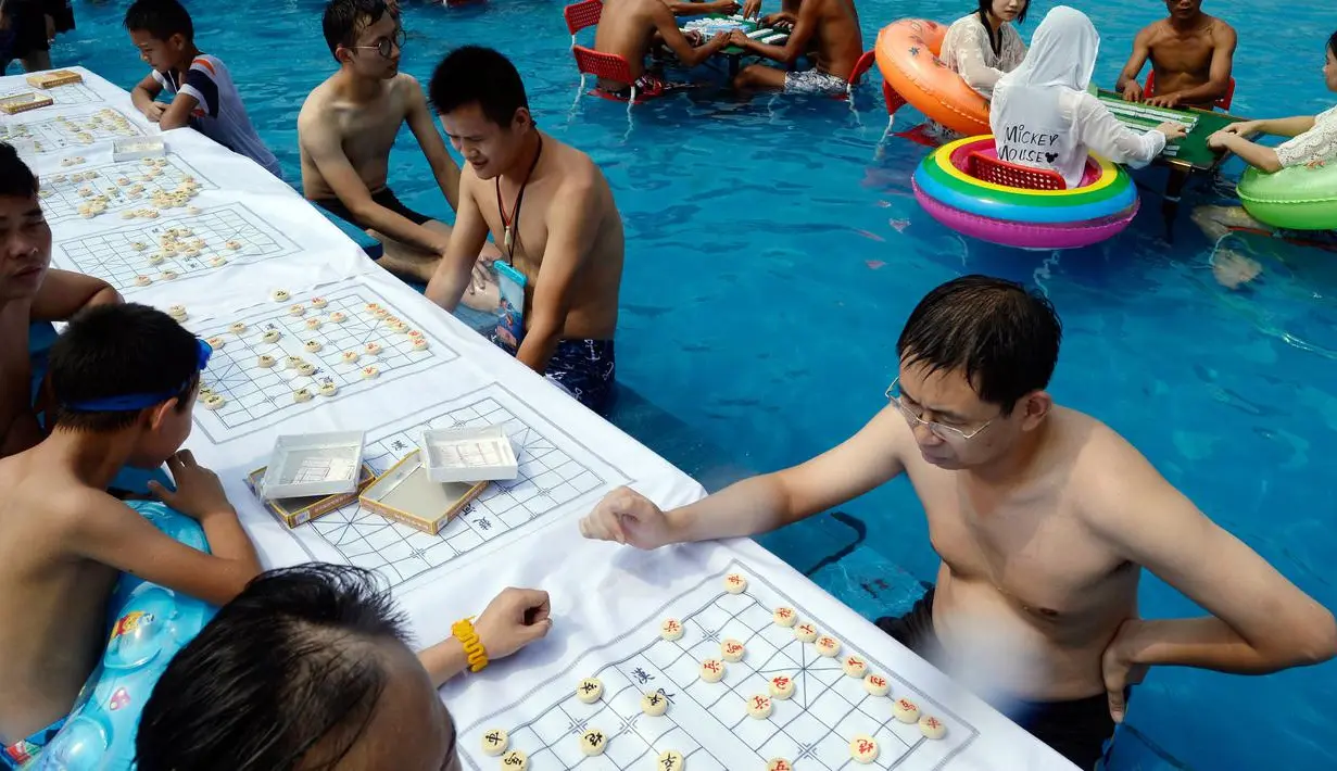 Sejumlah orang bermain catur di dalam kolam renang saat cuaca panas melanda wilayah Chongqing di Tiongkok, Rabu (2/8). Tiongkok saat ini dilaporkan sedang mengalami cuaca panas dengan suhu di beberapa daerah hampir mencapai 40 derajat celcius. (STR / AFP)