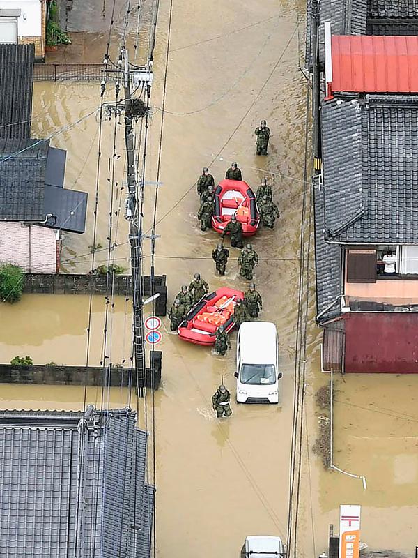 Pasukan Bela Diri Jepang menyusuri banjir saat operasi penyelamatan di Takeo, Prefektur Saga, Jepang, Rabu (28/8/2019). Perintah evakuasi 240 ribu warga di Kyushu dan sekitarnya dikeluarkan usai seorang warga dilaporkan tewas akibat terkena imbas hujan deras di Kota Saga. (Kyodo News via AP)