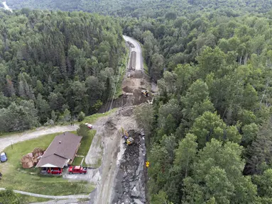 Para kru mulai memperbaiki bagian jalan raya 170 yang tersapu air di Riviere-Eternite, Quebec, Minggu, 2 Juli 2023. (Jacques Boissinot/The Canadian Press via AP)