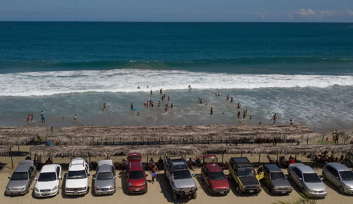 Mobil wisatawan diparkir di sepanjang pantai Los Angeles yang baru-baru ini dibuka kembali di La Guaira, Venezuela, Jumat (23/10/2020). Pemberlakuan lockdown yang ketat akibat COVID-19 memaksa penutupan pantai di seluruh negeri pada Maret lalu dan dibuka kembali minggu ini. (AP/Matias Delacroix)