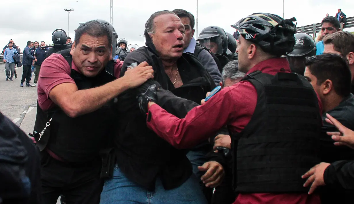 Menteri Keamanan Provinsi Buenos Aires Sergio Berni (tengah) diselamatkan dari protes di Buenos Aires, Argentina, Senin (3/4/2023). Berni dihajar sekelompok sopir bus yang tengah berdemo. (Andres Pelozo/AFP)