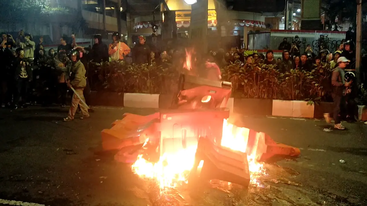 Massa membakar water barrier dan berbagai benda saat unjuk rasa di depan Mapolresta Malang Kota pada Jumat, 29 Agustus 2025 (Liputan6.com/Zainul Arifin)