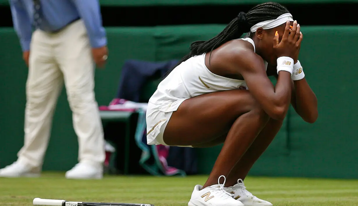 Petenis Cori Gauff menutupi wajahnya usai berhasil mengalahkan Venus Williams selama pertandingan babak pertama Grand Slam Wimbledon di London (1/7/2019). Cori merupakan petenis AS berusia 15 tahun yang berhasil mengalahkan Venus Williams. (AP Photo/Tim Ireland)