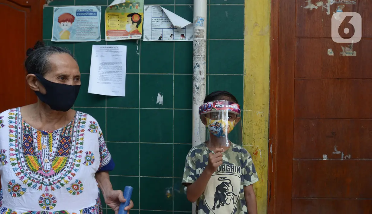 Warga mengenakan masker melihat penyemprotan disinfektan di pemukiman rumah warga  RW 01 Jakarta Pusat, kamis (9/7/2020). Penyemprotan ini untuk mencegah penyebaran virus corona (COVID-19). (merdeka.com/Imam Buhori)
