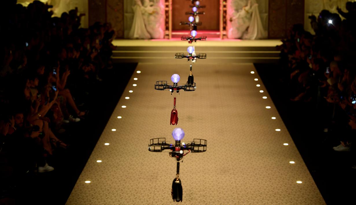 Deretan pesawat tanpa awak (drone) membawa koleksi tas tangan Dolce & Gabbana pada Milan Fashion Week 2018, Minggu (25/). Drone ini keluar dari belakang panggung, lalu terbang sambil membawa koleksi tas yang harganya terbilang selangit (Miguel MEDINA/AFP)