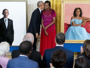 Mantan Presiden AS Barack Obama mencim istrinya, mantan ibu negara Michelle Obama setelah meresmikan lukisan mereka yang akan menjadi koleksi Gedung Putih di Ruang Timur Gedung Putih, Washington, Rabu (7/9/2022). Kedua gambar itu merupakan karya Robert McCurdy dan terlihat lebih seperti potret. (AP Photo/Andrew Harnik)