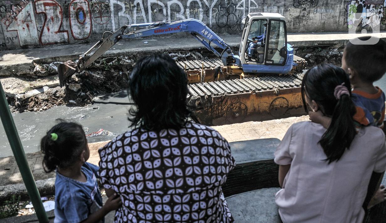 Warga menyaksikan petugas saat pengerukan lumpur di Kali Sentiong, Kecamatan Johar Baru, Rabu (22/9/2021). Pengerukan lumpur Kali Sentiong sekaligus mencegah banjir di kawasan tersebut yang kerap terjadi saat musim hujan. (merdeka.com/Iqbal S. Nugroho)