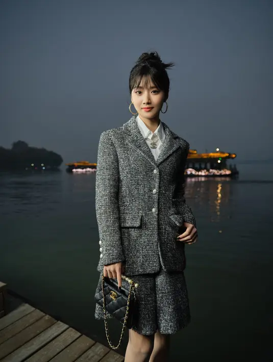 Lu Yuxiao, yang dikenal dengan gaya preppy-nya, tampil manis dengan tweed blazer dan mini skirt. Ia melengkapi penampilannya dengan kemeja dan dasi, menciptakan tampilan yang chic dan youthful. Gaya ini menunjukkan sisi lain dari Chanel yang tetap bisa dikenakan oleh berbagai kalangan usia. [Dok/Chanel].
