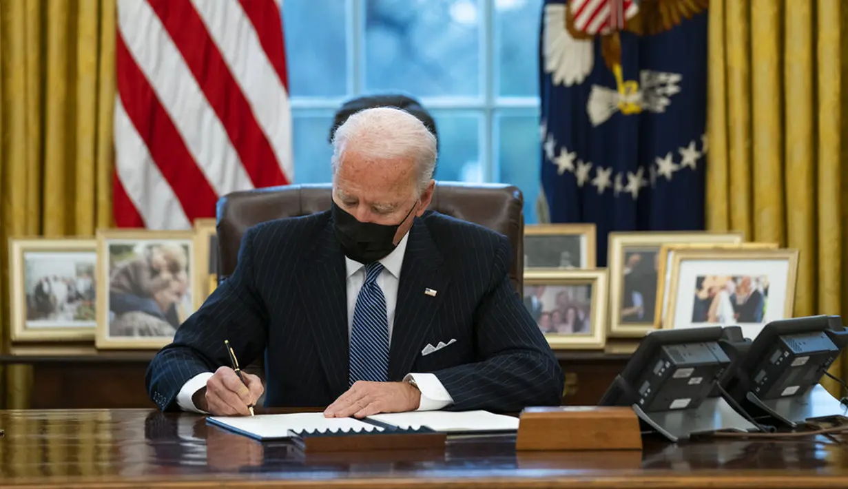 Presiden Amerika Serikat Joe Biden menandatangani Perintah Eksekutif yang membatalkan larangan bagi transgender untuk masuk militer AS pada era Donald Trump di Kantor Oval Gedung Putih, Washington, Senin (25/1/2021). (AP Photo/Evan Vucci)