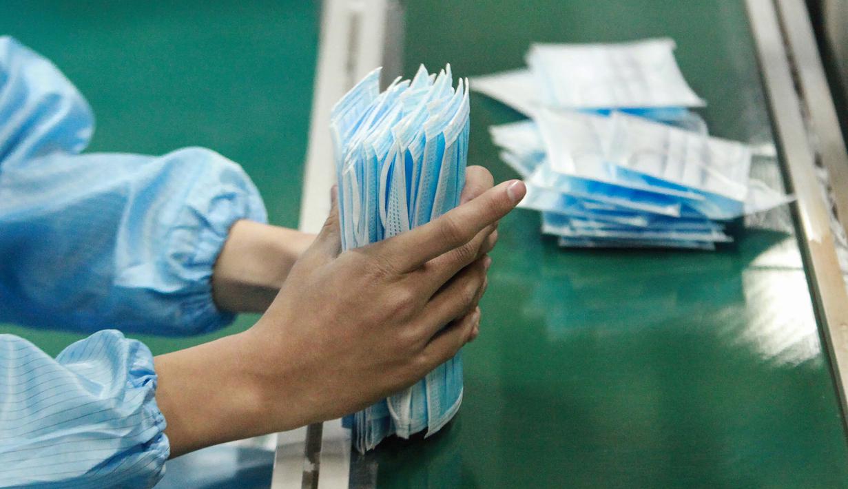 Pekerja memproduksi masker di sebuah pabrik di Yangzhou, Provinsi Jiangsu, China, Senin (27/1/2020). Masker tersebut diproduksi untuk mendukung pasokan bahan medis saat wabah virus corona melanda China. (STR/AFP)