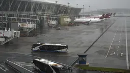 Bus dan pesawat penumpang diparkir di landasan setelah semua penerbangan dibatalkan di Bandara Internasional Pudong, Shanghai, Minggu (25/7/2021). China telah menutup jalur kereta api dan pelabuhan, serta membatalkan jadwal penerbangan sebelum topan In-Fa diperkirakan mendarat. (AP Photo/Andy Wong)