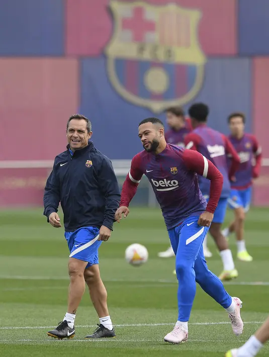 Pelatih interim Barcelona, Sergi Barjuan (kiri) dan Memphis Depay menghadiri sesi latihan menjelang lanjutan Liga Spanyol melawan Deportivo Alaves di Barcelona, Kamis (29/10/2021). Latihan pertama Barcelona usai Ronald Koeman dipecat, dipimpin oleh Sergi Barjuan. (Josep LAGO/AFP)