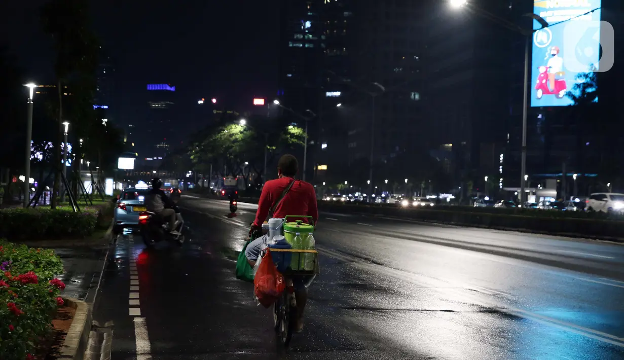 Pedagang kopi keliling melintas di jalan Jenderal Sudirman, Jakarta, Selasa (15/9/2020). Guna mengurangi pola penyebaran COVID-19, Pemda DKI Jakarta kembali menerapkan PSBB dengan membatasi aktivitas warga, perdagangan maupun perkantoran. (Liputan6.com/Helmi Fithriansyah)