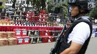 Petugas berjaga di dekat ribuan botol minuman keras bukti kasus penyelundupan di Polda Metro Jaya, Jakarta, Senin (18/9). Kerugian negara akibat penyelundupan ilegal ini diperkirakan mencapai Rp 58,06 miliar. (Liputan6.com/Immanuel Antonius)