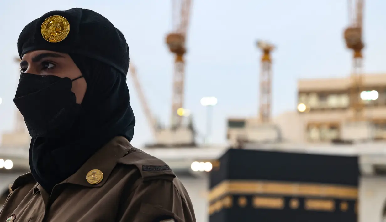 Seorang polisi wanita Saudi berjaga-jaga saat jemaah mengelilingi Ka'bah pada rangkaian ibadah haji di Masjidil Haram, Makkah, Selasa (20/7/2021). Kini, para personel perempuan bergabung dengan rekan-rekan pria mereka dalam menjaga kota suci selama musim haji. (Fayez Nureldine / AFP)